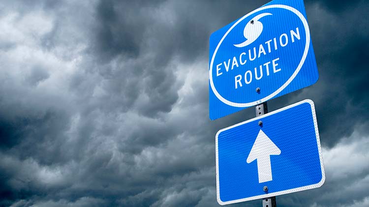 Hurricane evacuation route sign with storm clouds in the background.